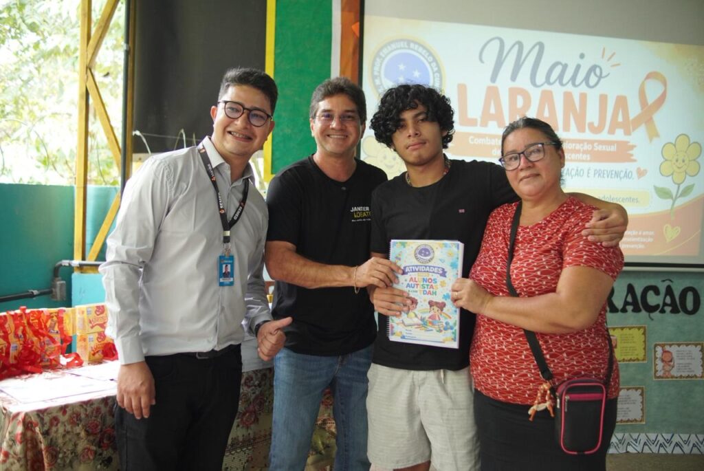 Quatro pessoas posam em uma escola durante entrega de apostilas sobre autismo e TDAH promovida pelo vereador Jander Lobato em Manaus.