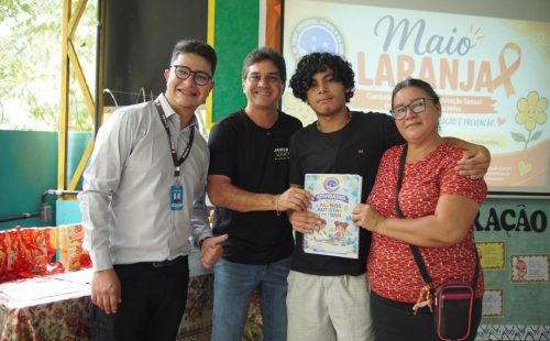 Quatro pessoas posam em uma escola durante entrega de apostilas sobre autismo e TDAH promovida pelo vereador Jander Lobato em Manaus.